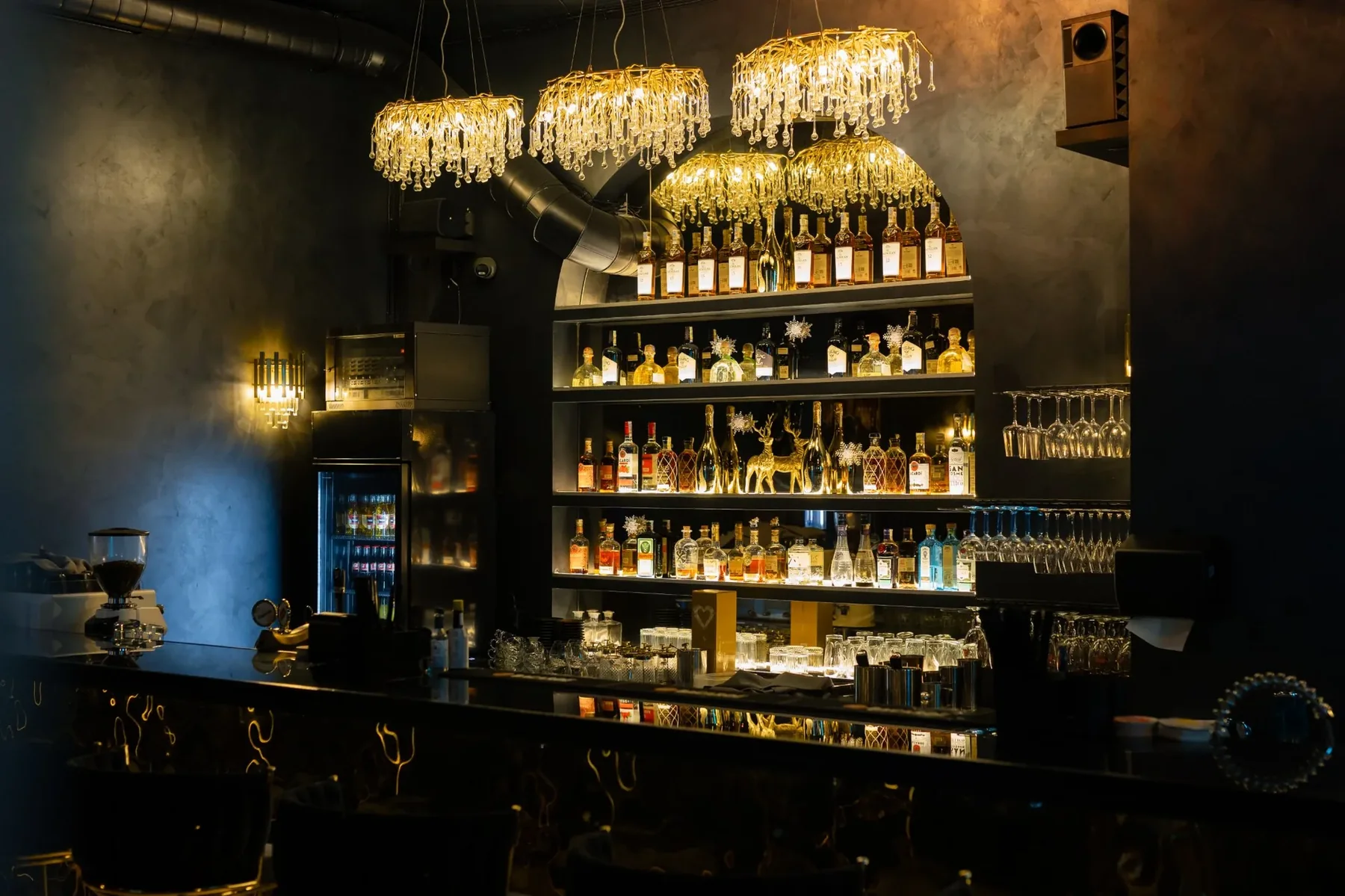 Crystal chandeliers above the bar and the lit bottle shelves