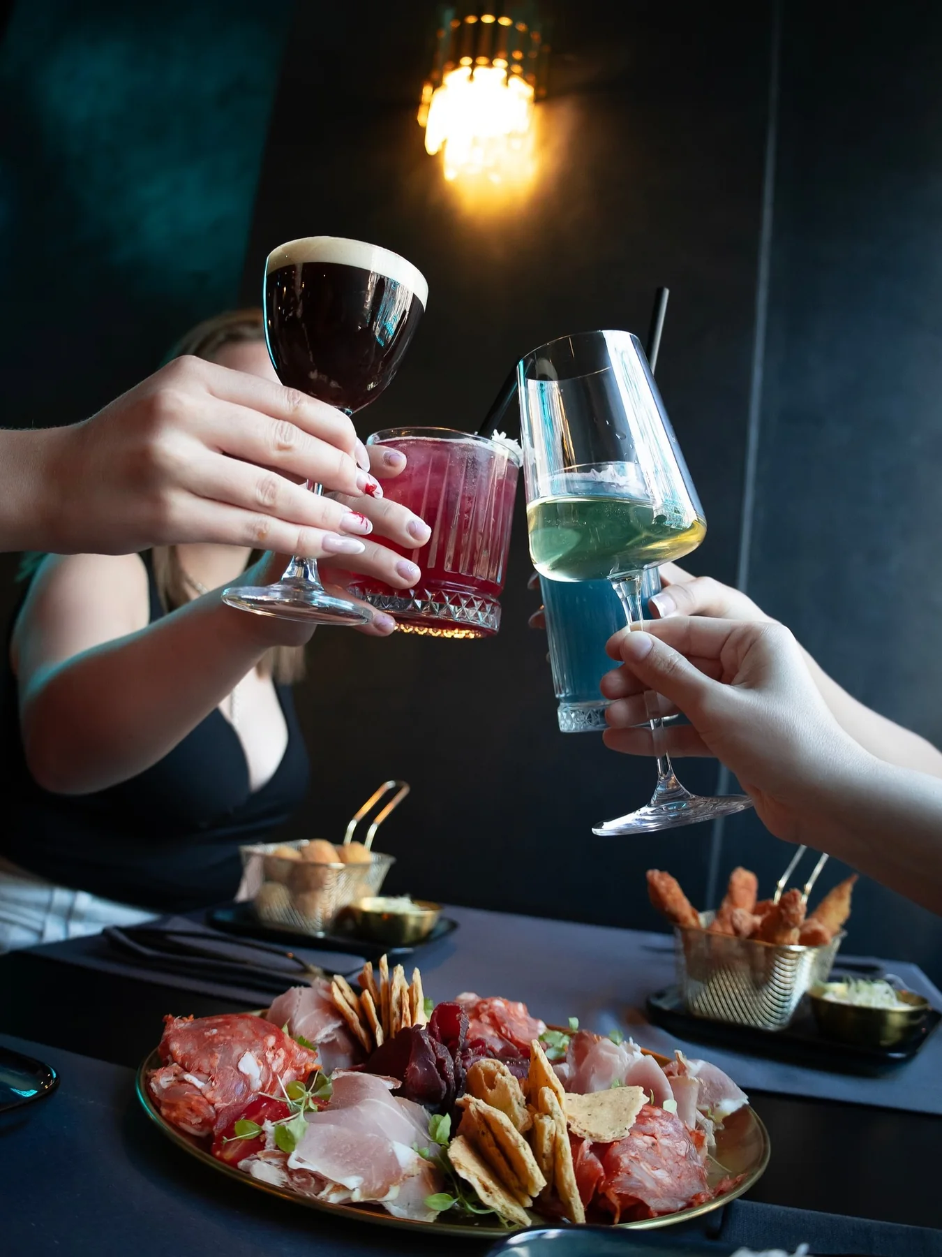 Four glasses meeting over a charcuterie board