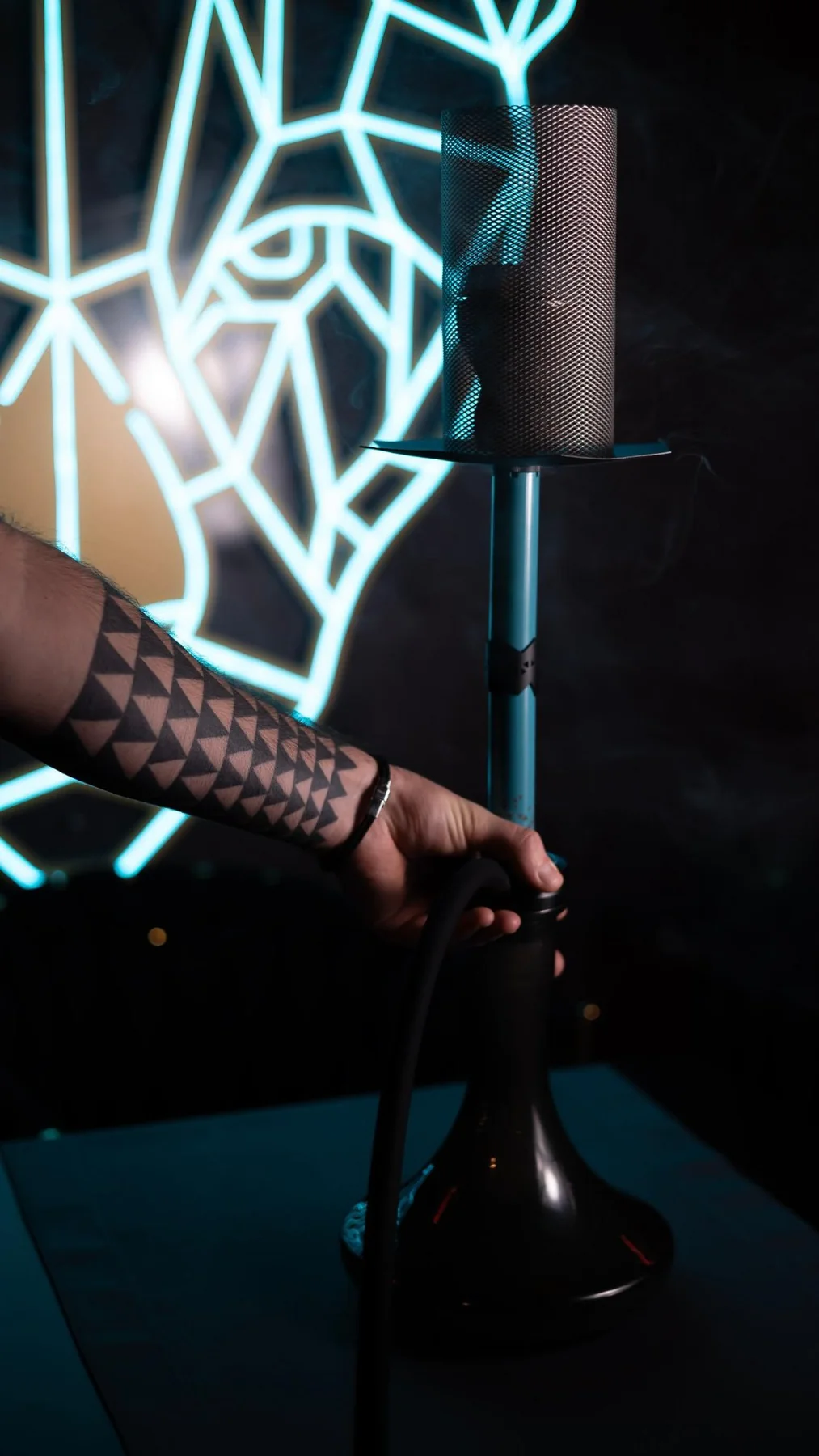 A shisha set up at the table beneath the neon panther