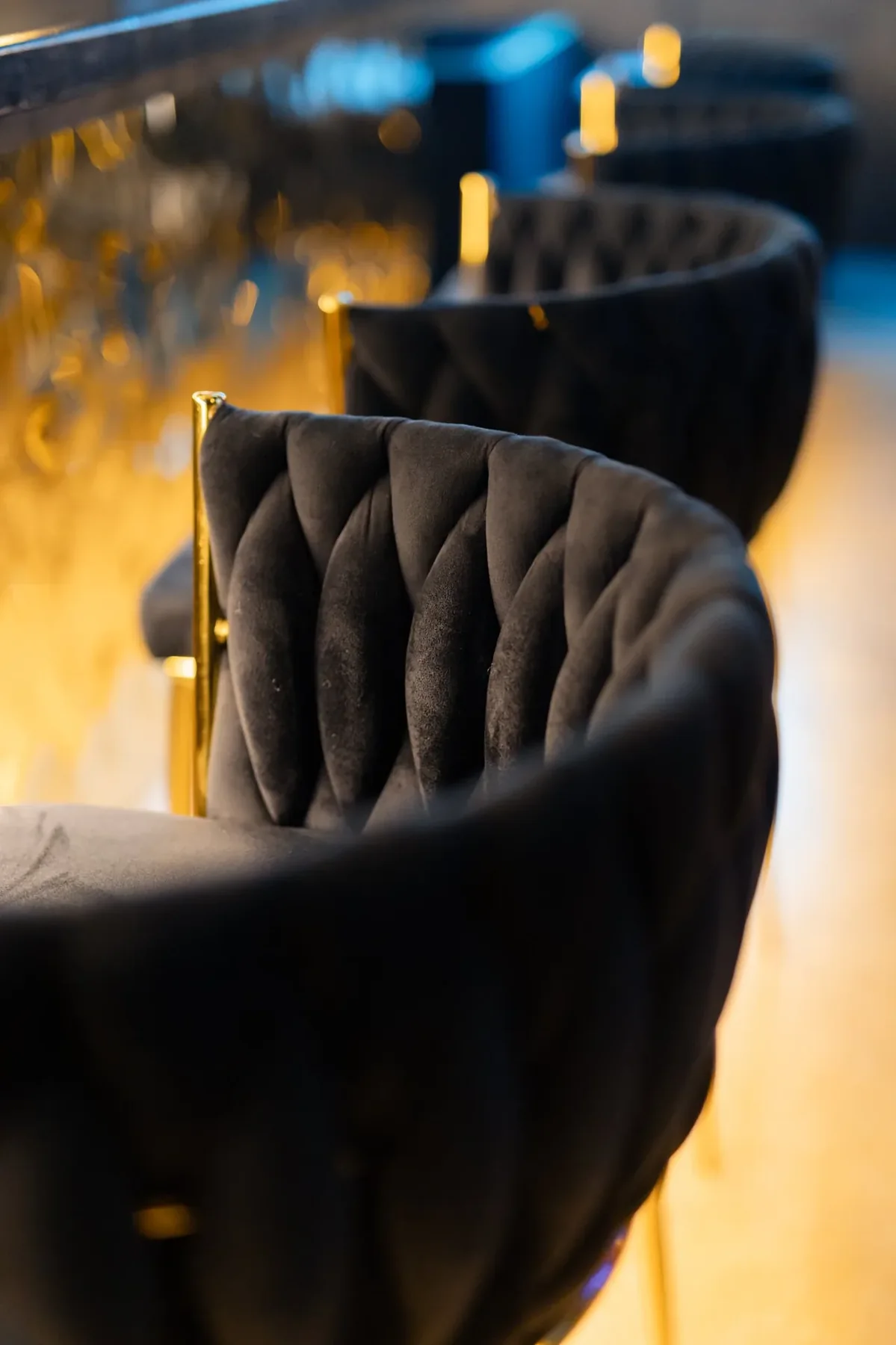 Velvet bar stools on brass legs along the black bar